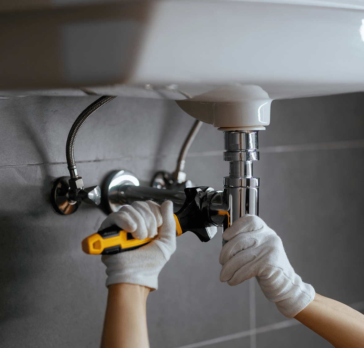 Gloved hands tightening sink pipe connection